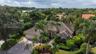 Single-story residence featuring a tile roof, paved driveway, two-car garage, and established landscaping with mature palm trees