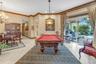 Spacious room featuring neutral tile flooring, crown molding, a decorative multi-light chandelier, a stained-glass style pendant fixture, and large sl