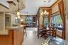 Kitchen featuring stone-finish countertops, natural wood cabinetry, built-in corner shelving, ceramic tile flooring, and decorative multi-light chande