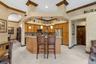 Kitchen featuring custom wood cabinetry, stone countertops, a multi-tiered peninsula island, tile flooring, and hanging pendant lighting