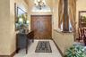 Foyer featuring double wood entry doors, an arched transom window, a decorative chandelier, tile flooring, and a stone-topped half wall with an orname
