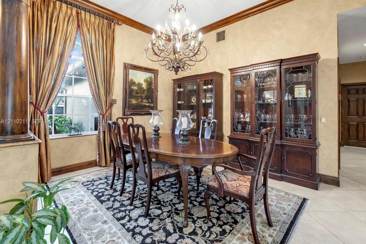 Dining area featuring crown molding, neutral textured walls, tile flooring, and an ornate multi-arm chandelier
