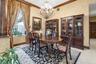 Dining area featuring crown molding, neutral textured walls, tile flooring, and an ornate multi-arm chandelier
