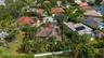Aerial view of residence featuring a tile roof, multi-car driveway, lush mature landscaping, and white perimeter fencing