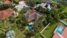 Aerial perspective featuring a tile roof, private swimming pool, mature tropical landscaping, and paved driveway