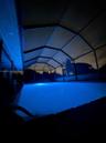 In-ground swimming pool enclosed by a structural screen lanai