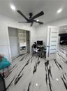 High-contrast polished tile flooring, matte black ceiling fan, white interior door with frosted glass panels, and built-in closet shelving
