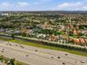 Aerial perspective featuring suburban residential development with mature palm trees and proximity to major thoroughfare