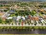 Aerial perspective of a single-family residence featuring a paved driveway, attached garage, and waterfront location