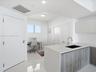 Kitchen featuring stone-finish countertops, grey wood-finish cabinetry, a square undermount sink with a gooseneck faucet, and polished tile flooring