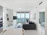 Open-concept interior featuring polished tile flooring, floor-to-ceiling glass doors, and integrated kitchen appliances