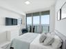 Floor-to-ceiling glass sliding doors opening to a private balcony, polished white tile flooring, and water scenery
