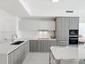 Contemporary kitchen featuring dual-tone cabinetry, quartz countertops, integrated stainless steel appliances, and a recessed stainless steel sink wit