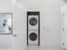 Stackable white front-load washer and dryer unit housed in a recessed closet
