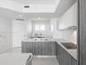 Modern kitchen featuring flat-panel cabinetry with wood-finish lower cupboards, solid surface countertops, an undermount sink with a gooseneck faucet,