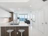 Kitchen featuring high-gloss cabinetry, wood-finish lower cabinets, stone countertops, and floor-to-ceiling glass sliding doors opening to a balcony