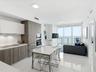 Kitchen featuring two-tone cabinetry with wood-finish and flat-panel white uppers, integrated appliances, white stone countertops, and polished tile f