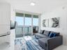 Floor-to-ceiling sliding glass door, private balcony with metal railing, and neutral flooring