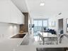 Modern kitchen featuring flat-panel cabinetry, light-toned countertops, built-in cooktop, and large-format tile flooring, accented by floor-to-ceiling