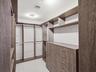 Walk-in closet featuring floor-to-ceiling wood-finish cabinetry, built-in shelving, integrated hanging rods, and a multi-drawer chest