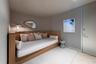 Custom built-in wood bed frame with integrated shelving, light-toned wood-finish flooring in a herringbone pattern, and neutral wall color