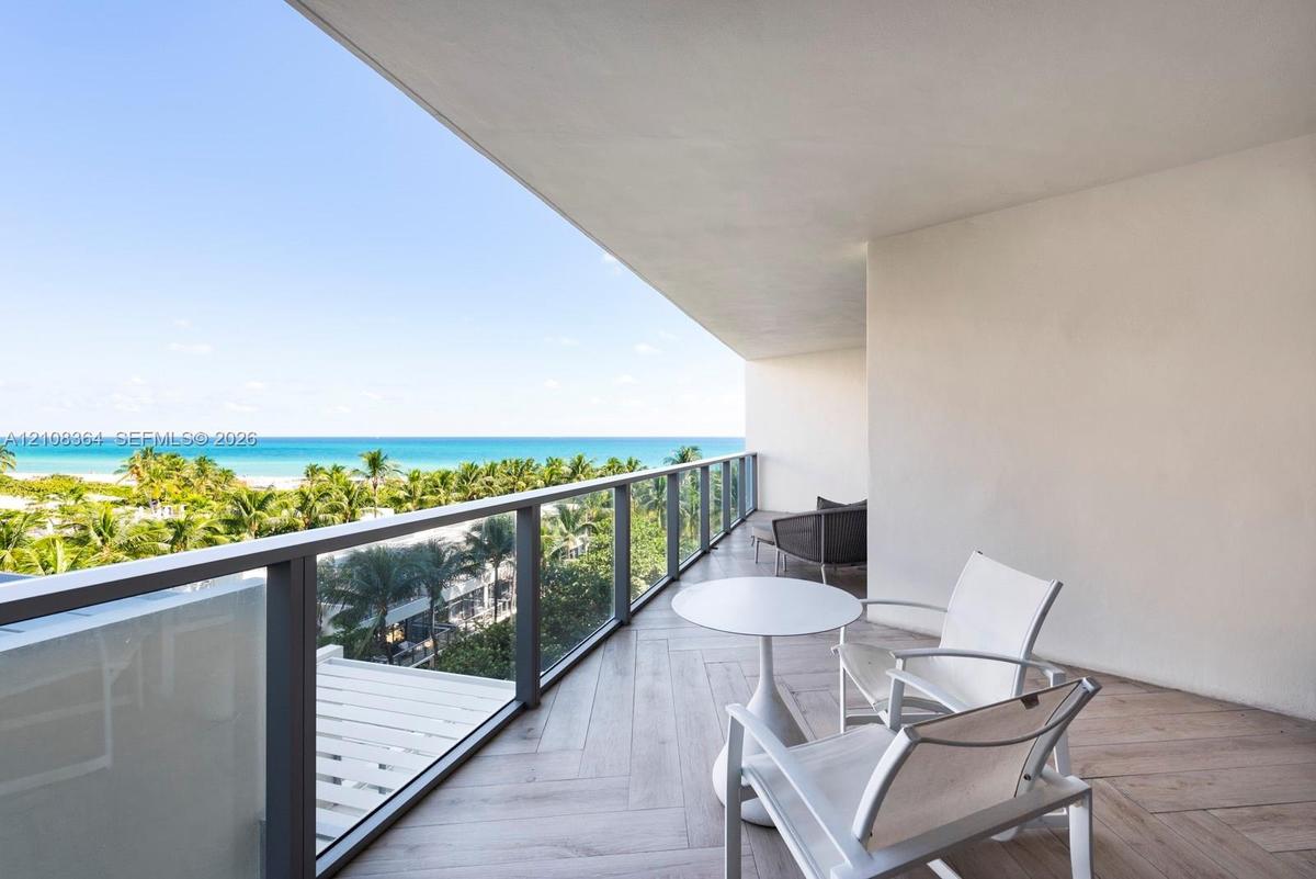 Covered balcony with herringbone-patterned wood-finish flooring and a metal-framed glass railing