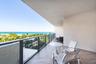 Covered balcony with herringbone-patterned wood-finish flooring and a metal-framed glass railing