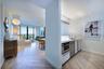 Herringbone wood-finish flooring, white flat-panel cabinetry, integrated stainless steel microwave, quartz countertops, and floor-to-ceiling glass sli