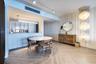 Herringbone wood-finish flooring, vertical slat wall paneling, tiered crystal pendant light fixture, track lighting, and built-in minimalist cabinetry
