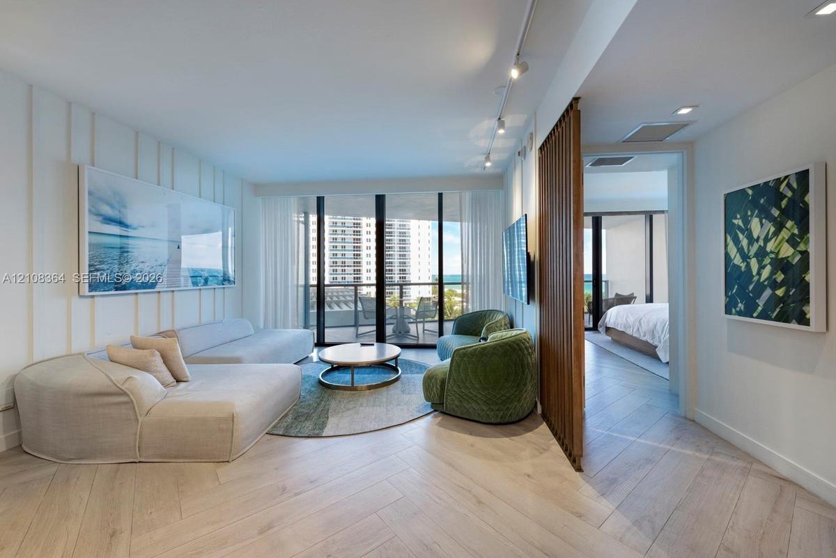 Herringbone-patterned wood-finish flooring, floor-to-ceiling glass doors, decorative vertical slat room divider, recessed track lighting, and board-an