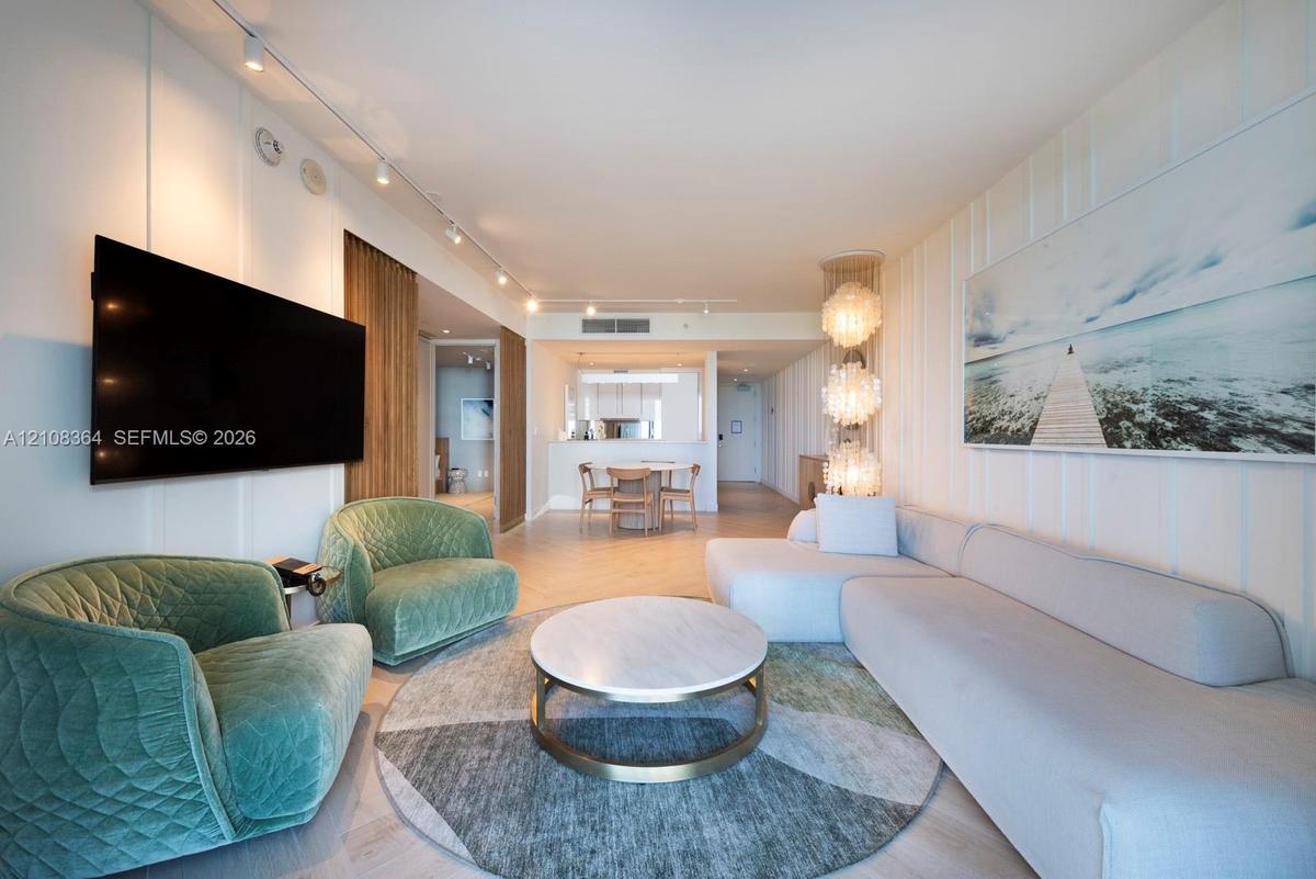 Vertical wall paneling, track lighting, herringbone-patterned wood-finish flooring, and multi-tiered decorative pendant lighting