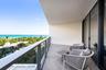 Private covered balcony featuring herringbone-patterned flooring, glass-paneled railing, and expansive ocean scenery