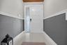 Entryway featuring a grid-patterned door with a vertical glass side panel, two-tone wall finish with decorative chair rail molding, and large-format t