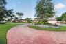 Curved hexagonal paver driveway, manicured lawn, stone-accented landscaping, and attached garage