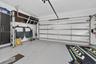 Two-car garage featuring a sectional overhead door, epoxy-coated flooring, and built-in vertical cabinetry