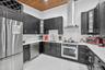 Kitchen featuring dark cabinetry, solid-surface countertops, wood-plank ceiling, stainless steel appliances, and a glass-front display cabinet