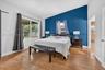 Vaulted ceiling, wood-finish flooring, accent wall, and large windows with outdoor exposure