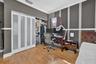 Room featuring wood-finish flooring, crown molding, chair rail trim, and a built-in closet system with frosted glass panels