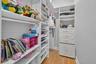 Walk-in closet featuring white built-in shelving, integrated storage drawers, a hanging rod, and wood-finish flooring