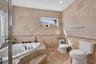 Bathroom featuring floor-to-ceiling stone-tile wall finishes, a recessed jetted soaking tub with a tiled surround, and integrated tile flooring