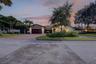 Single-story residence featuring a tile roof, an attached garage with a finished door, a paved driveway, and mature landscaping