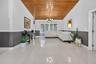 Vaulted wood-plank ceiling, large-format tile flooring, multi-pane window, and decorative chair rail molding