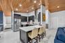 Kitchen featuring vaulted wood-plank ceilings, a central island with a solid-surface countertop, dark-toned cabinetry, stainless steel appliances, and