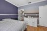Room featuring wood-finish flooring, crown molding, and a walk-in closet with built-in shelving
