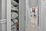 Built-in floor-to-ceiling shelving, crisp white louvered doors, polished tile flooring, and chair rail molding