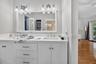 Double vanity featuring white cabinetry, integrated sinks, a white countertop, large wall-mounted mirror, and multi-bulb light fixtures