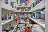 Walk-in storage pantry featuring U-shaped white shelving and wall-mounted metal support brackets