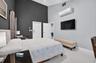 High-ceiling interior featuring a dual-tone accent wall, wall-mounted climate control unit, and crisp light-colored flooring