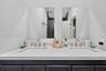 Dual-sink vanity with white stone countertop, rectangular undermount basins, brushed nickel widespread faucets, and twin frameless mirrors