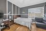 Bedroom featuring wood-finish flooring, accent-painted walls with chair rail molding, crown molding, and horizontal privacy shades